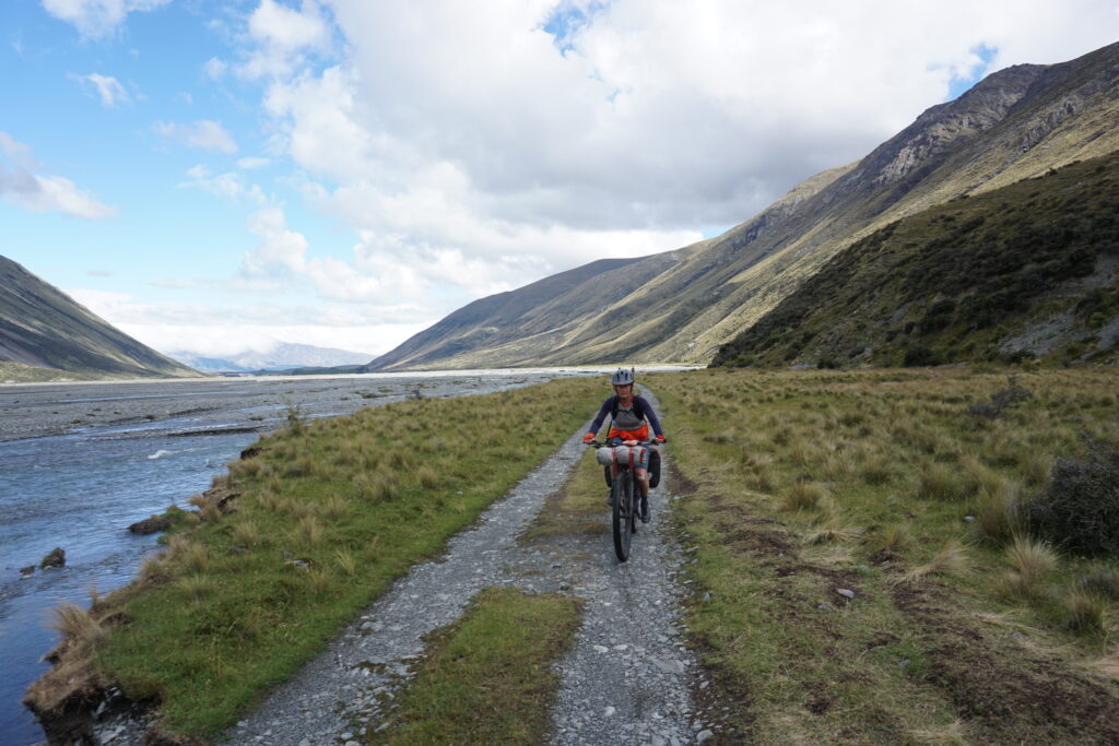 a female bikepacker enjoys a new zealand valley